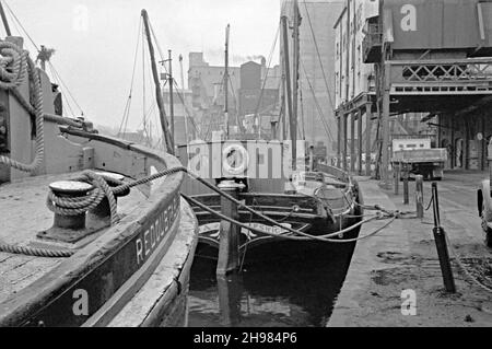 Das Wet Dock im Hafen von Ipswich, Suffolk, England, UK, fotografiert in den letzten Tagen des Handelsverkehrs Mitte 1960s. Hier werden noch immer Thames-Segelschiffe, hauptsächlich für den Getreidehandel, auf dem Fluss Orwell und der Nordsee eingesetzt. Das Zentrum ist ‘Ena’, ein Holzkahn, der 1906 auf dem Hof von W B McLearon in Harwich, Essex gebaut wurde. Sie ist ein bemerkenswertes Dunkirk ‘kleines Schiff’ aus dem Zweiten Weltkrieg, das angeblich 100 Männer im Jahr 1940 gerettet haben soll. Seit dem Jahr 1990s hat sich das Gebiet stark sanieren lassen, und die Handelstätigkeit des Hafens befindet sich nun weiter flussabwärts – ein Vintage-Foto aus dem Jahr 1960s. Stockfoto