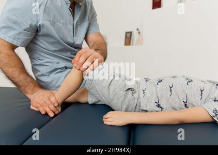 Knieschmerzlinderung in der Klinik. Arzt Physiotherapeut, der heilende Behandlung am Bein des Patienten macht. Therapeut gibt Bein- und Kälbermassage. Osteopathie Stockfoto