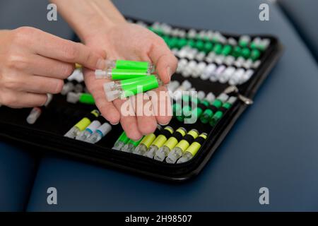 Der Arzt hält kleine Ampullen in den Händen. Nahaufnahme einer kleinen Ampulle mit einem Impfstoff in der Hand des Arztes. Reagenzglas für Allergietest halten. Allergietests Stockfoto