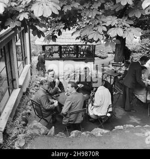 Cheddar, Sedgemoor, Somerset, 20/06/1953. Eine Gruppe von Menschen saß vor einem Café in Cheddar, während eines Laing-Personals, das nach Minehead ging. Im Jahr 1947, nach einer siebenjährigen Pause, hatte Laing seine „Ausflüge in die Umgebung“ für Mitarbeiter und ihre Familien wiederbelebt, wobei die Reisen im Mai und Juni stattfinden. Diese Reise war für ihre Mitarbeiter in der Südwestregion aus Bristol und Plymouth. Die Aufnahme scheint in Cheddar aufgenommen worden zu sein, da sie auch hier auf der Reise angehalten haben. Stockfoto
