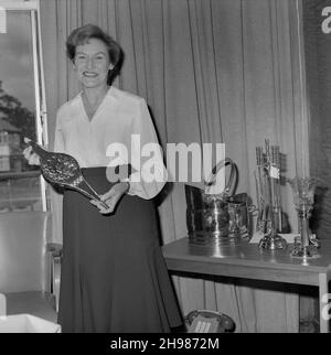 Mary Coldicott hält ein ornamentales Geschenk aus Messing, während ihrer Pensionspräsentation, 01/08/1986. Ein Porträt von Mary Coldicott, die während ihrer Pensionspräsentation ein ornamentales Geschenk aus Messing mit weiteren Geschenken auf dem Tisch neben ihr hielt, begann Mary Coldicott 1971 bei der Firma Laing in der Buchhaltung zu arbeiten. Danach verbrachte sie fast drei Jahre als Kassiererin, bevor sie zur Pensions-/Investment-Abteilung wechselte. Das Negativregister zeichnet den Ort des Fotos als „Carlisle Building“ auf. Stockfoto
