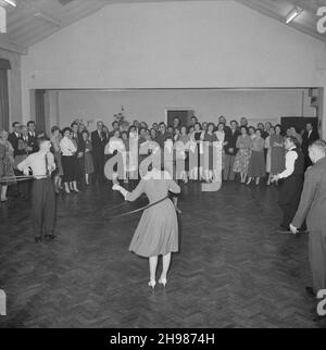 Goodwyn Hall, Mill Hill, Barnett, London, 09/01/1959. Eine Menge Leute, die Männer und Frauen beim Hula Hooping auf einer Neujahrsparty beobachten. Diese Neujahrsparty fand in der Goodwyn Hall in Mill statt und war für Mitglieder des Laing's Sports Club zusammen mit ihren Frauen und Freunden. Die Popularität von Hula Hooping, die auf dem Foto zu sehen ist, nahm Ende 1950s ihren Ausweg. Stockfoto