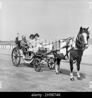 Gorleston-on-Sea, Great Yarmouth, Norfolk, 09/06/1956. Ein Mann mit zwei Mädchen in einem Pferdewagen auf der Promenade von Gorleston-on-Sea, während eines Tages nach Great Yarmouth für Laing-Mitarbeiter und Familien. Im Jahr 1947, nach einer siebenjährigen Pause, hatte Laing seine „Ausflüge in die Umgebung“ für Mitarbeiter und ihre Familien wiederbelebt, wobei die Reisen im Mai und Juni stattfinden. Im Frühsommer 1956 wurden zwölf Ausflüge organisiert. Dieser Ausflug war für Mitarbeiter von Laing aus den östlichen Grafschaften Englands, darunter Kings Lynn, Thurleigh, Welwyn, Hatfield, Stanstead, Waltham Abbey, Chelmsford, Stevenage und Stockfoto