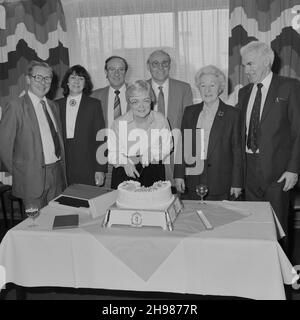 John Laing and Son Limited, Page Street, Mill Hill, Barnett, London, 30/03/1987. Frau Joan Kirby, mit einer Gruppe von Freunden und Kollegen, posierte während ihrer Präsentation im Ruhestand in Mill Hill mitten im Kuchen schneiden. Joan Kirby kam 1955 zu Laing als Sekretärin für Herrn Waldrum, der für das Personal zuständig war. Sie arbeitete dann für verschiedene andere Personen, darunter John Renshaw. Joan kam 1982 in die Wohlfahrtsabteilung von Laing und zog sich 1987 nach 32 Jahren aus dem Unternehmen zurück. Die Schreibmaschine neben dem Kuchen in diesem Bild wurde Joan als Ruhestandsgeschenk überreicht. Stockfoto