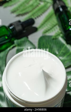 Eine Dose Creme wird auf den grünen Hintergrund gelegt. Stockfoto