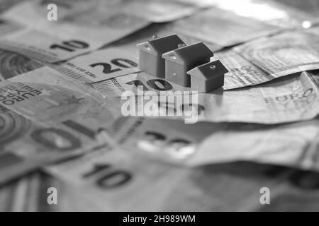 Tisch mit Euro-Banknoten bedeckt mit Häusern auf der Oberseite. Immobilieninvestitionskonzept Stockfoto