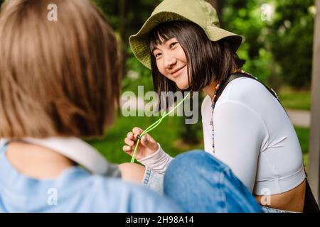 Multirassische zwei Frauen sprechen und lächeln, während sie sich im grünen Park ausruhen Stockfoto