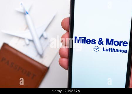 Miles More Lufthansa Airline-Logo auf dem Handybildschirm mit Flugzeug, Reisepass und Bordkarte im Hintergrund. Das Konzept der mobilen Anwendung der Fluggesellschaften. November 2021, San Francisco, USA Stockfoto