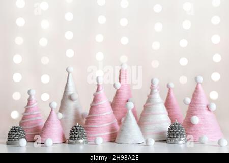 DIY Weihnachtsbäume ist aus rosa Garn. Umweltfreundliche, flauschige Weihnachtsdekor auf glänzendem Hintergrund Stockfoto