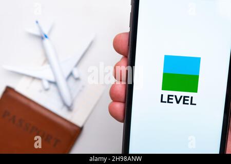 Level-Airline-Logo auf dem Handybildschirm mit Flugzeug, Reisepass und Bordkarte im Hintergrund. Das Konzept der mobilen Anwendung der Fluggesellschaften. November 2021, San Francisco, USA Stockfoto