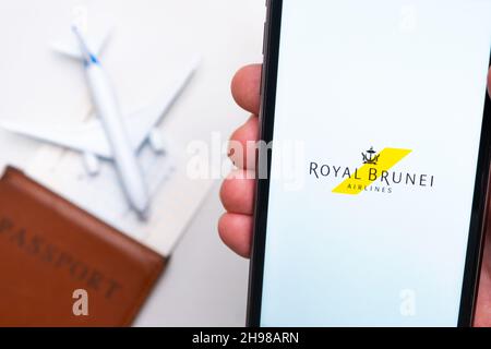 Royal Brunei Airlines-Logo auf dem Handybildschirm mit Flugzeug, Reisepass und Bordkarte im Hintergrund. Das Konzept der mobilen Anwendung der Fluggesellschaften. November 2021, San Francisco, USA Stockfoto