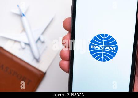 Pan am Airline-Logo auf dem Handybildschirm mit einem Flugzeug, einem Reisepass und einer Bordkarte im Hintergrund. Das Konzept der mobilen Anwendung der Fluggesellschaften. November 2021, San Francisco, USA Stockfoto