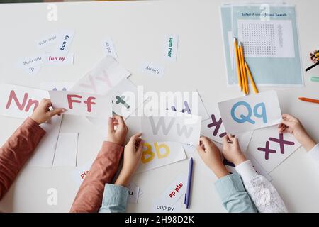 Nahaufnahme von Kindern, die zusammen mit Karten am Tisch sitzen und Englisch lernen Stockfoto