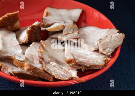 Schweinebauch in einem Teller auf schwarzem Hintergrund. Fleisch in Stücke geschnitten. Stockfoto