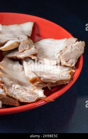 Schweinebauch in einem Teller auf schwarzem Hintergrund. Fleisch in Stücke geschnitten. Stockfoto