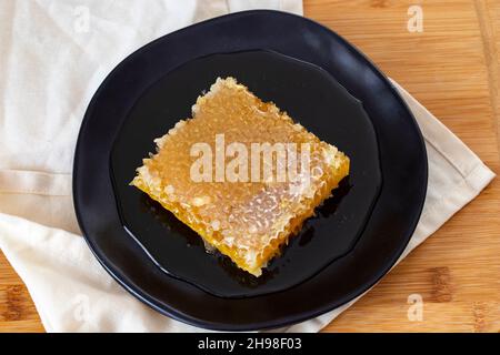 Bio-Honigwabe auf Holzgrund. Honig auf dem Teller Stockfoto