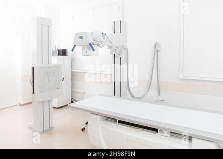 Röntgenabteilung im modernen Krankenhaus. Röntgenraum mit Scangerät und leerem Bett. Techniker, der ein Röntgengerät anpasst. Scannen von Brust, Herz Stockfoto