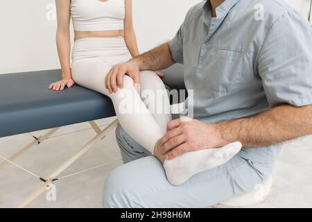 Knieschmerzlinderung in der Klinik. Arzt Physiotherapeut, der heilende Behandlung am Bein des Patienten macht. Therapeut gibt Bein- und Kälbermassage. Osteopathie Stockfoto