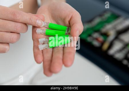 Der Arzt hält kleine Ampullen in den Händen. Nahaufnahme einer kleinen Ampulle mit einem Impfstoff in der Hand des Arztes. Reagenzglas für Allergietest halten. Allergietests Stockfoto