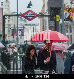 MADRID, SPANIEN - 31. Oktober 2021: Blick auf ein Paar mit einem Regenschirm an einem regnerischen Nachmittag in der Gran Via, Madrid, Spanien Stockfoto