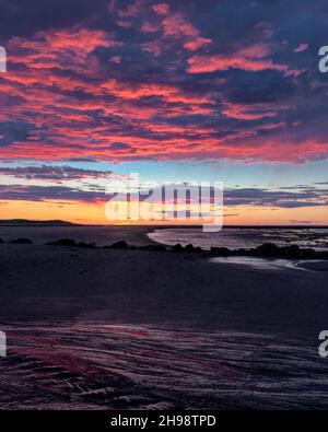 Pink Purple Orange dramatischer Sonnenuntergang am Strand in der Abenddämmerung Stockfoto