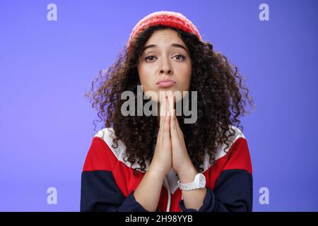 Nahaufnahme von niedlichen weiblichen Freundin Betteln bringen ihre Lieblings-Süßigkeiten halten Hände in beten Falten Lippen und starrte mit Engel unschuldigen Blick auf Stockfoto