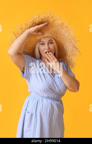 Überrascht reife Frau in Strohhut auf farbigem Hintergrund Stockfoto