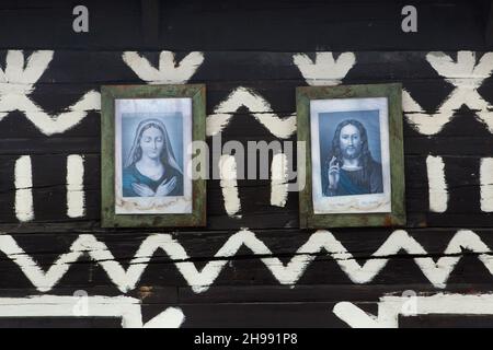 Bilder von Jesus Christus und der Jungfrau Maria, die auf dem traditionellen Blockhaus mit weißen linearen Mustern im Dorf Čičmany in der Region Žilina in der Slowakei aufgestellt wurden. Stockfoto