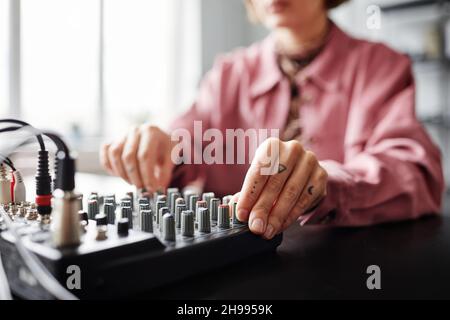 Nahaufnahme der jungen weiblichen Schöpferin mit Audio-Mischpult beim Einrichten von Aufnahmematerial im Studio, Kopierraum Stockfoto