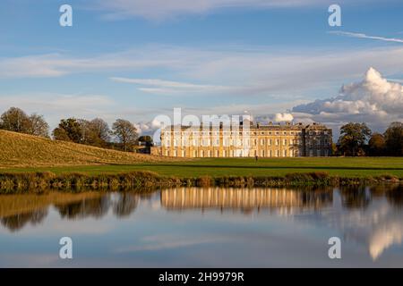 Der Petworth Park und das Haus spiegeln sich im späten Herbstlicht mit einem atemberaubenden Himmel darüber Stockfoto