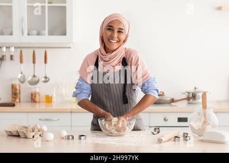 Glückliche Islamische Dame In Hijab Backen In Der Küche, Herstellung Von Teig Für Kekse Stockfoto