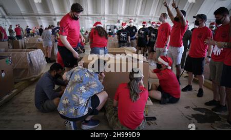 Yigo, Usa. 04th Dez 2021. Freiwillige packen gespendete Güter und schmücken Lufttropfenbündel mit Botschaften zur Unterstützung der jährlichen Operation Christmas Drop 70th auf der Andersen Air Force Base am 4. Dezember 2021 in Yigo, Guam. Jedes Jahr im Dezember werden die Luftbesatzungen 55 Inselnationen im gesamten Südost-Pazifik Nahrungsmittel, Vorräte, Unterrichtsmaterialien und Werkzeuge von AirDrop spenden. Kredit: 1lt. Jade Watkins/US Airforce Foto/Alamy Live News Stockfoto