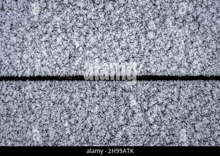 Eine Wand aus Holzplanken, die an einem frostigen Morgen mit weißem Frost bedeckt ist. Stockfoto