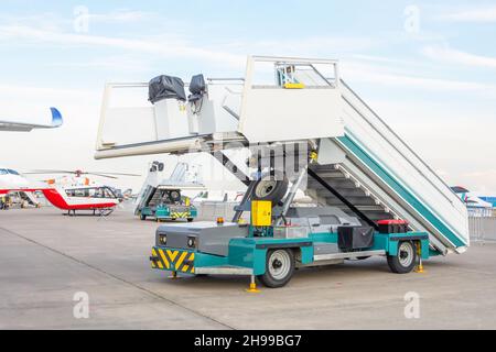 Maschine mobile Leiter Treppe am Flughafen auf dem Flugplatz in der Ferne Flugzeuge und Hubschrauber Stockfoto