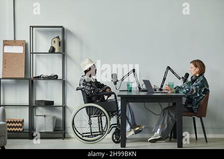 In voller Länge Porträt der Person im Rollstuhl geben Interview während der Aufnahme Podcast im Studio, Copy Space Stockfoto
