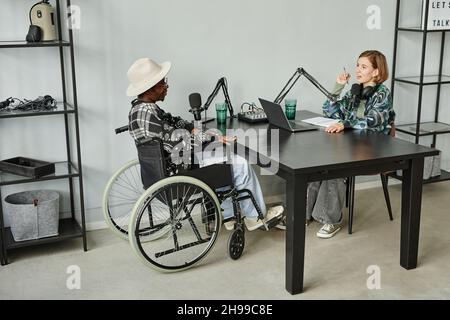 In voller Länge Porträt von afroamerikanischen Person im Rollstuhl geben Interview während der Aufnahme Podcast im Studio Stockfoto