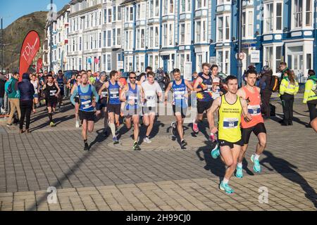 Läufer,Teilnehmer,in,Aberystwyth 10k,Kilometer,Lauf,Rennen,durchgeführt,in,Aberystwyth,Cardigan Bay,Küste,Küste,an,A,sonnig,aber,windig,Dezember,Winter,Winter,Tag,Mittel,Westen,Wales,Ceredigion,Ceredigion County,Welsh,GB,UK,Vereinigtes Königreich,Großbritannien,Großbritannien,Britisch,Europa,europäisch, Stockfoto