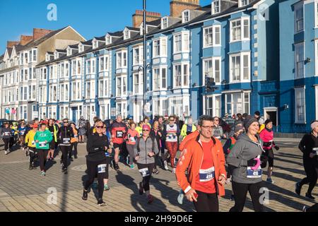 Läufer,Teilnehmer,in,Aberystwyth 10k,Kilometer,Lauf,Rennen,durchgeführt,in,Aberystwyth,Cardigan Bay,Küste,Küste,an,A,sonnig,aber,windig,Dezember,Winter,Winter,Tag,Mittel,Westen,Wales,Ceredigion,Ceredigion County,Welsh,GB,UK,Vereinigtes Königreich,Großbritannien,Großbritannien,Britisch,Europa,europäisch, Stockfoto