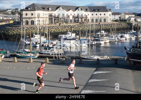 Läufer,Passing,Aberystwyth Harbour,Aberystwyth Marina,Teilnahme,an,Aberystwyth 10k,Kilometer,Lauf,Rennen,durchgeführt,in,Aberystwyth,Cardigan Bay,Küste,Küste,auf,A,sonnig,aber,windig,Dezember,Winter,Winter,Tag,Mittel,Westen,Wales,Ceredigion,Ceredigion County,Walisisch,GB,UK,Europa,Großbritannien Stockfoto