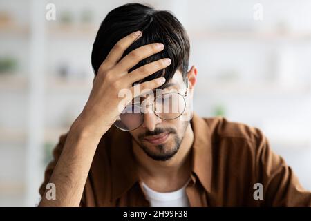 Gestresster Mitarbeiter aus dem Nahen Osten, der unter Kopfschmerzen leidet Stockfoto