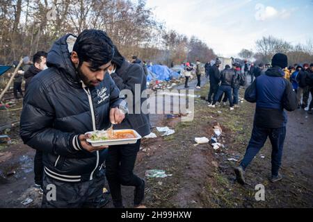 Dünkirchen, Frankreich. 05th Dez 2021. Ein Migrant, der von einer NGO in einem provisorischen Migrantenlager zu Mittag gegessen wird.Schätzungen zufolge leben derzeit etwa 800 Migranten/Flüchtlinge in der Region Dünkirchen in Nordfrankreich. Die meisten von ihnen warten auf ihre Möglichkeiten, entweder mit einem aufblasbaren Schlauchboot nach Großbritannien zu kommen oder sich in Lastwagen zu verstecken. Kredit: SOPA Images Limited/Alamy Live Nachrichten Stockfoto