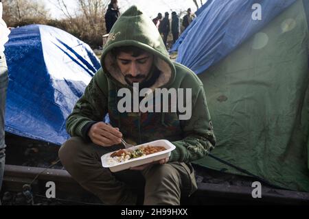 Dünkirchen, Frankreich. 05th Dez 2021. Ein Migrant, der von einer NGO in einem provisorischen Migrantenlager zu Mittag gegessen wird.Schätzungen zufolge leben derzeit etwa 800 Migranten/Flüchtlinge in der Region Dünkirchen in Nordfrankreich. Die meisten von ihnen warten auf ihre Möglichkeiten, entweder mit einem aufblasbaren Schlauchboot nach Großbritannien zu kommen oder sich in Lastwagen zu verstecken. Kredit: SOPA Images Limited/Alamy Live Nachrichten Stockfoto