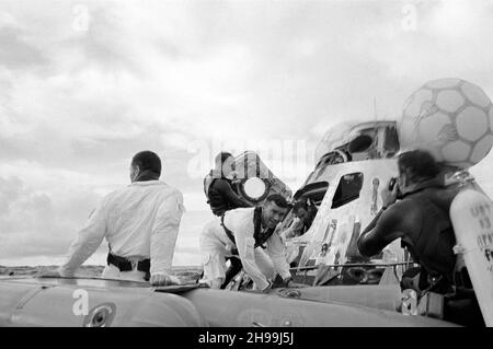 Ein Blick auf den Wasserstand der Apollo 13-Gewinnungsbetriebe im Südpazifik. Die drei Astronauten haben gesehen, wie sie ihr Raumschiff abregten. John L. Swigert Jr. (zurück zur Kamera), Kommandomodulpilot, ist bereits im Rettungsinsel. Fred W. Haise Jr., Mondmodul-Pilot, mit Blick auf die Kamera, tritt in das Rettungsinsel ein. James A. Lovell Jr., Commander, verlässt das Raumschiff im Hintergrund. Ein Unterwasser-Abbruchteam der US-Marine unterstützt die Bergung. Die drei Besatzungsmitglieder wurden mit dem Hubschrauber abgeholt und zum ersten Bergungsschiff, USS Iwo Jima, geflogen Stockfoto