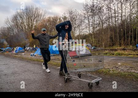 Dünkirchen, Frankreich. 05th Dez 2021. Migranten sehen, wie sie einen Supermarktwagen in ein provisorisches Migrantenlager schieben.Schätzungen zufolge leben derzeit rund 800 Migranten/Flüchtlinge in der Region Dünkirchen in Nordfrankreich. Die meisten von ihnen warten auf ihre Möglichkeiten, entweder mit einem aufblasbaren Schlauchboot nach Großbritannien zu kommen oder sich in Lastwagen zu verstecken. (Foto von Geovien so/SOPA Images/Sipa USA) Quelle: SIPA USA/Alamy Live News Stockfoto