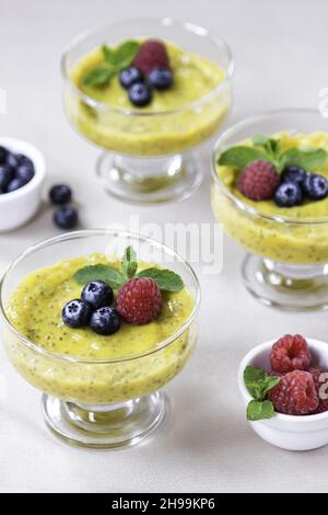 Ein vertikaler Schuss leckeren Mango-Chia-Pudding mit Himbeeren, serviert in Gläsern Stockfoto
