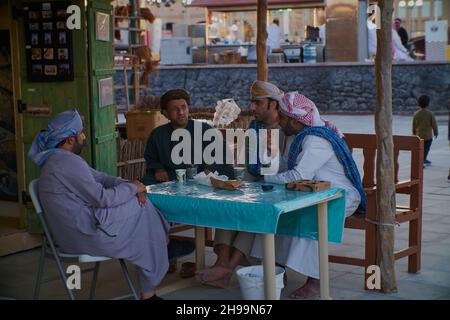 Gruppe traditioneller arabischer Fischer, die im Katara-Kulturdorf in Doha, Katar, während des elften traditionellen Dhow-Festivals in Katara, Tageslichtansicht sitzen Stockfoto