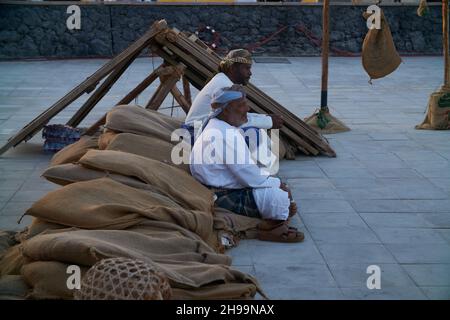 Gruppe traditioneller arabischer Fischer, die im Katara-Kulturdorf in Doha, Katar, während des elften traditionellen Dhow-Festivals in Katara, Tageslichtansicht sitzen Stockfoto