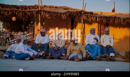 Gruppe traditioneller arabischer Fischer, die im Katara-Kulturdorf in Doha, Katar, während des elften traditionellen Dhow-Festivals in Katara, Tageslichtansicht sitzen Stockfoto