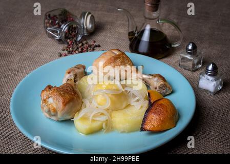 Zitronen-Hähnchenschenkel, garniert mit Kartoffeln und Zwiebeln, im Ofen gegarten. Stockfoto