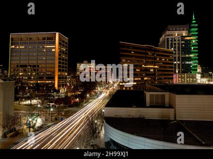 Die Lichter des Autos bei Nacht mit der beleuchteten Skyline von Boise Idaho Stockfoto